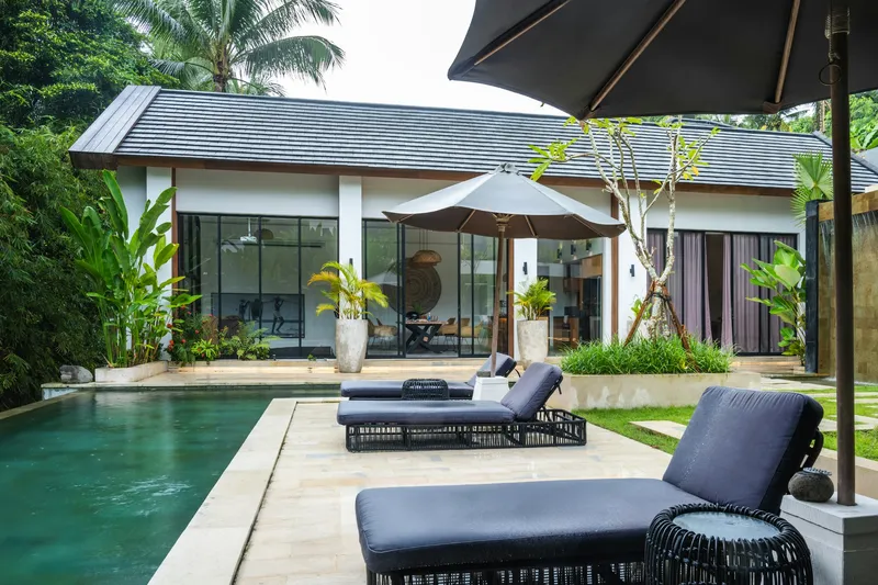 Piscina com espreguiçadeiras e chapéu-de-sol junto a uma moradia