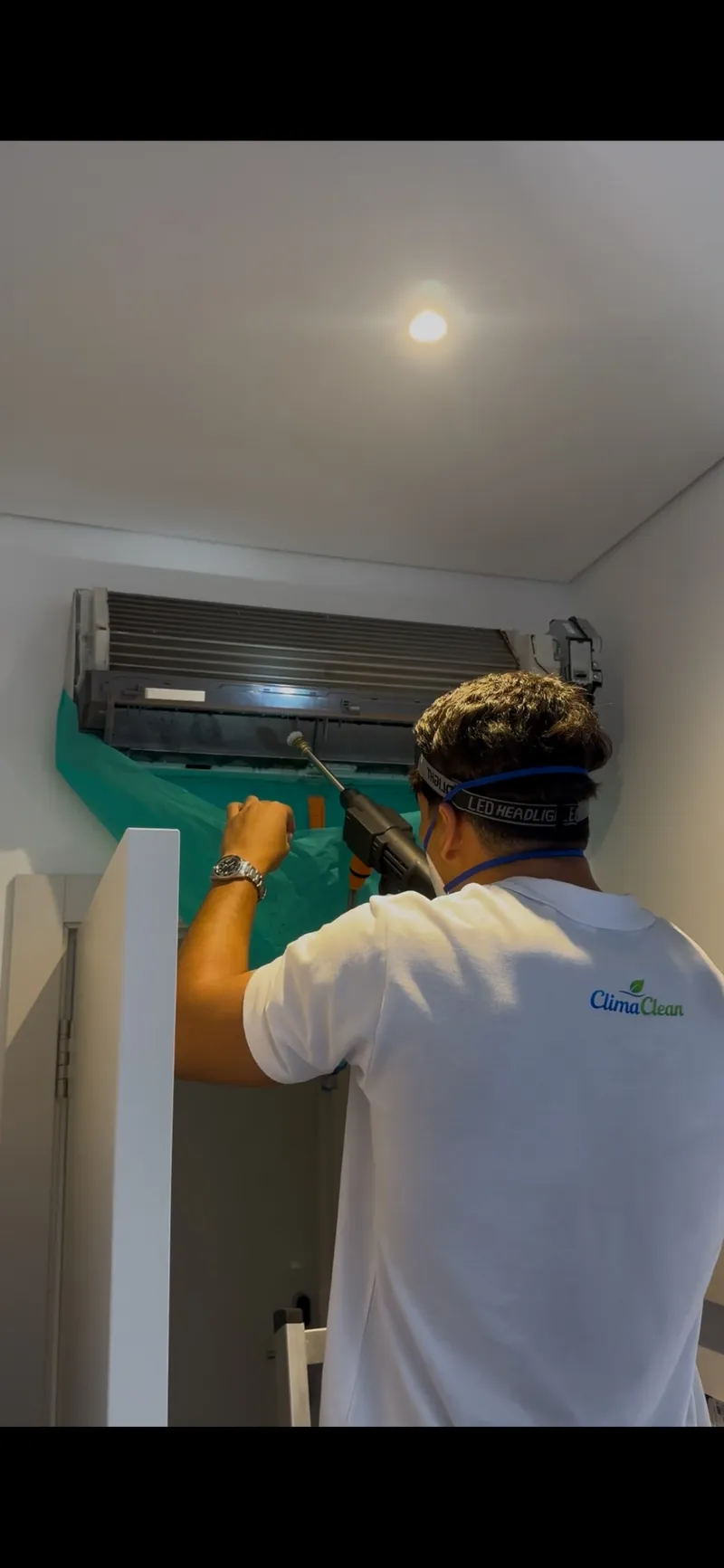 Técnico da ClimaClean com máscara de proteção a limpar a carcaça exterior de uma unidade de parede no final da intervenção