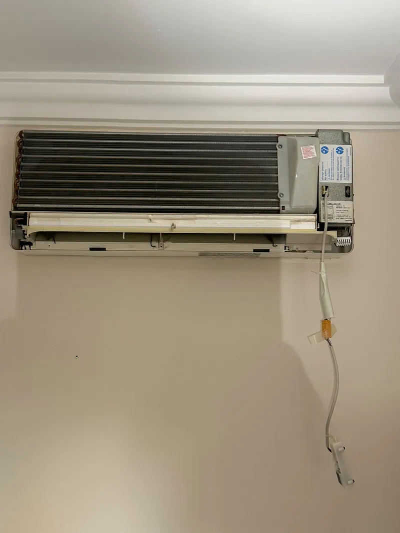 Unidade de ar condicionado de parede com a tampa frontal levantada, pronta para desmontagem e limpeza interior