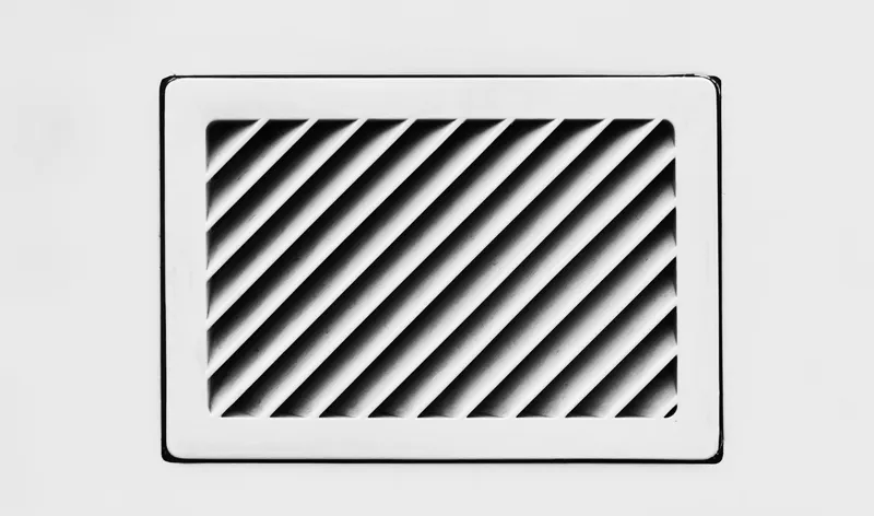 Grelha de ventilação cinzenta numa parede, em grande plano